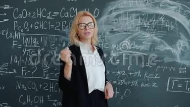 成人妇女在黑板附近的课堂上缓慢地教授科学